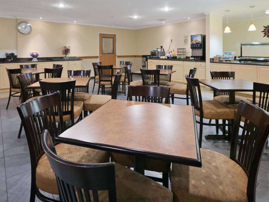 A restaurant with multiple tables and chairs, a clock on the wall, and a coffee machine.