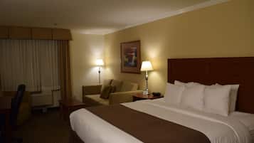 A hotel room with a large bed, a sofa, a desk, and two lamps.