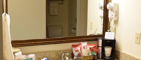 A bathroom with a sink, mirror, and toiletries.