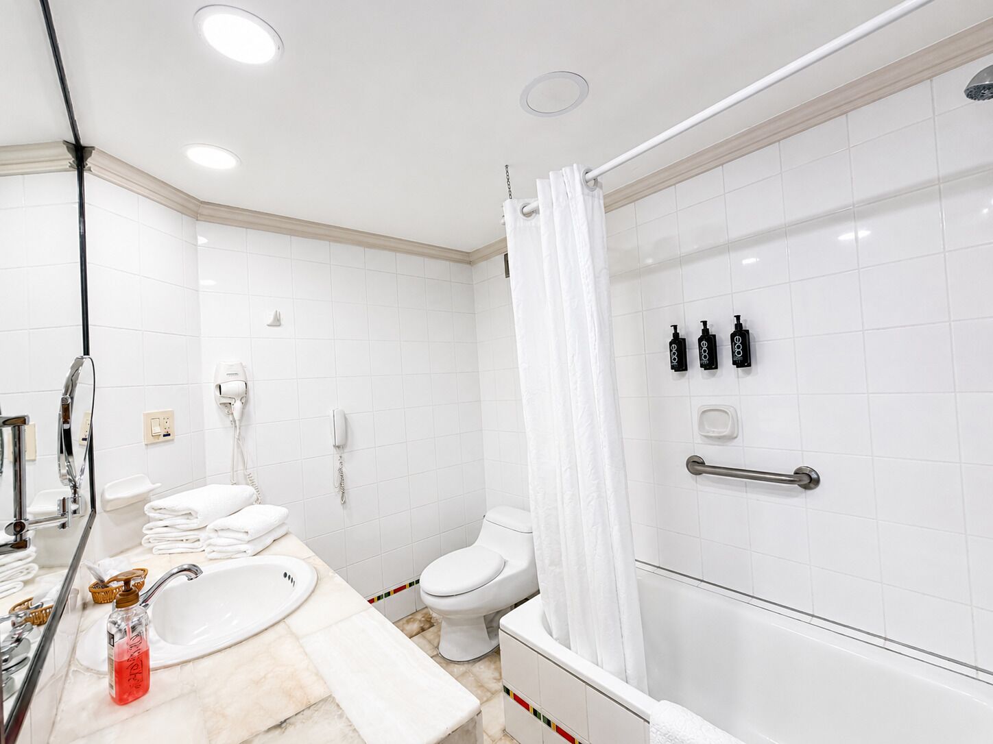 Un baño moderno con lavamanos, inodoro y ducha blancos.