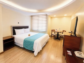 A hotel room with a bed, a desk with a computer, a telephone, and a window with blinds. - Hotel República (Quito)