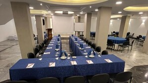 Uma sala de conferências com uma mesa comprida, cadeiras e um púlpito.