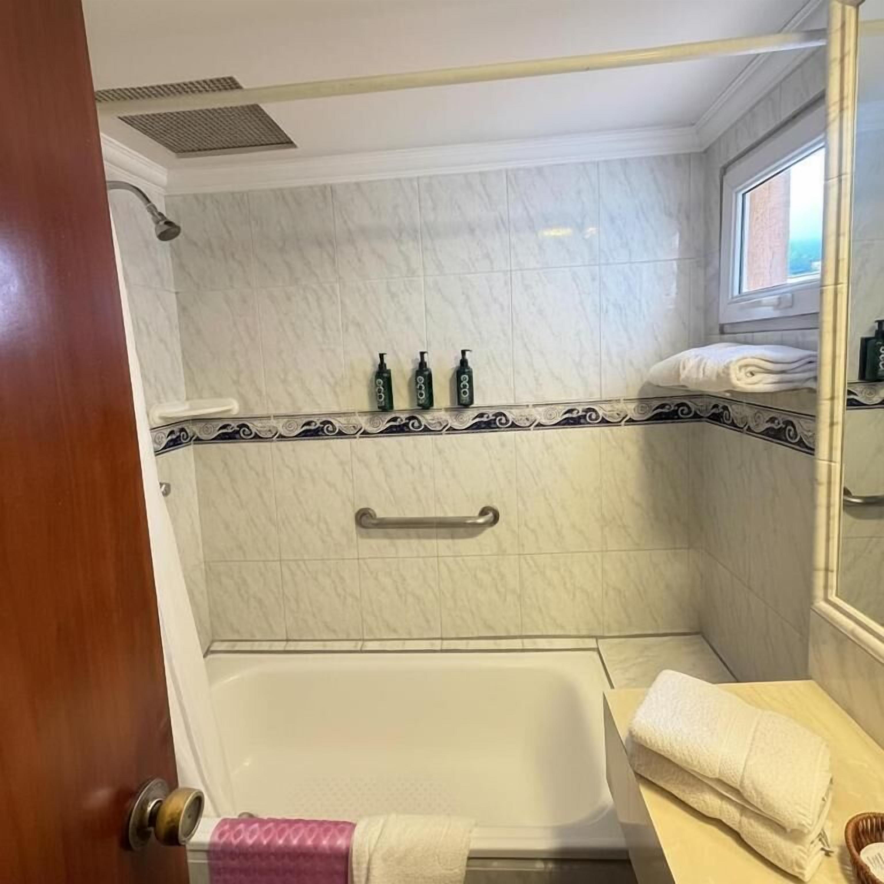 Un baño con bañera, un perchero y una ventana.