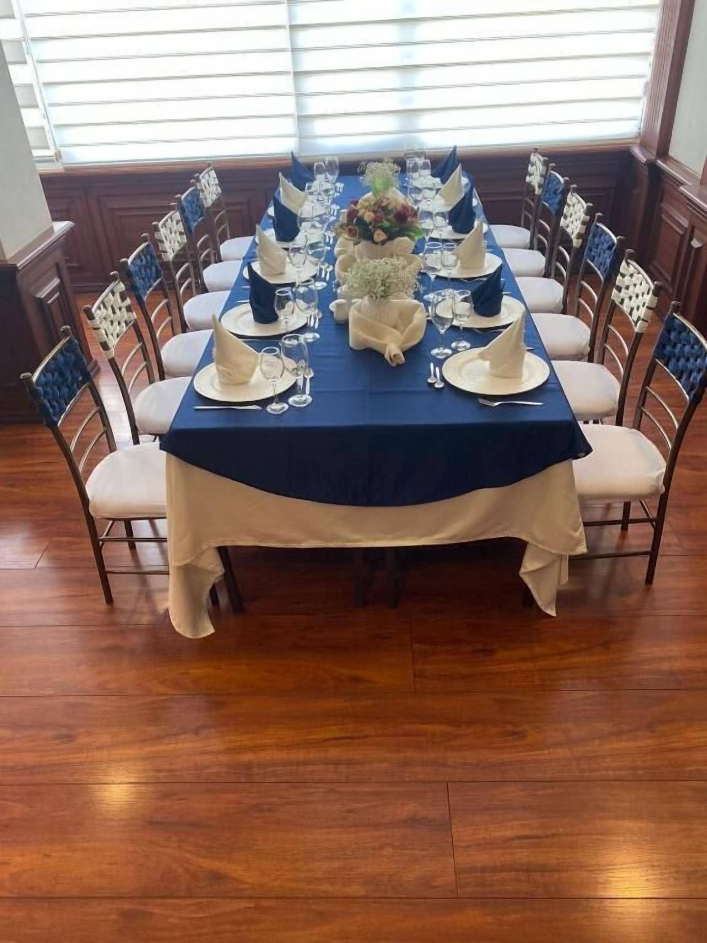 A dining table set for a meal with a blue tablecloth, white napkins, and a centerpiece.