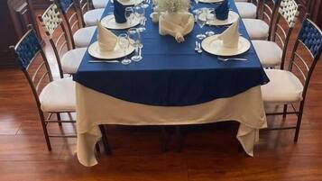 A dining table set for a meal with a blue tablecloth, white napkins, and a centerpiece.