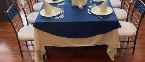 A dining table set for a meal with a blue tablecloth, white napkins, and a centerpiece.