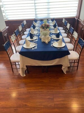 Une table à manger dressée pour un repas, avec une nappe bleue, des serviettes blanches et un centre de table.