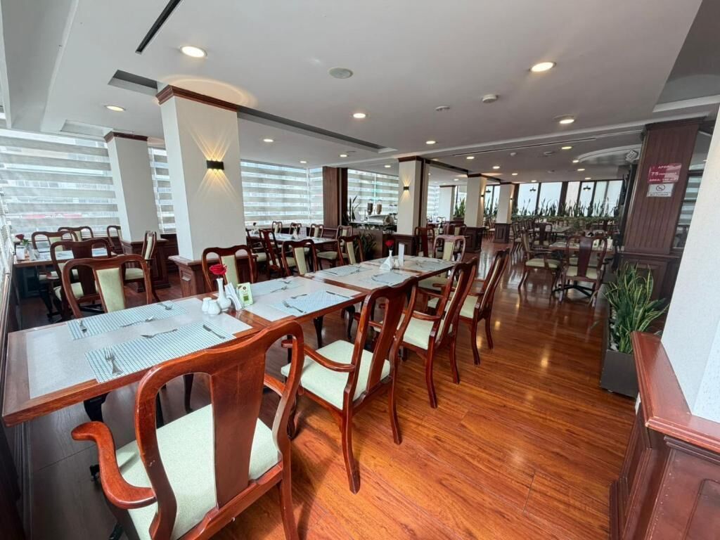 A conference room with long tables and chairs, wooden flooring, and large windows.