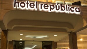 Entrada do Hotel Republica com design moderno, apresentando uma placa grande acima da entrada e uma escadaria que leva ao saguão.