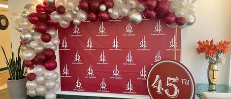 A hotel lobby with a red backdrop featuring the hotel's logo and a 45th anniversary banner.
