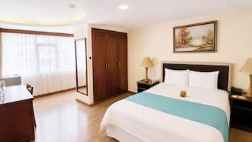 A hotel room with a bed, bedside tables, a wardrobe, a desk, and a window with curtains.
