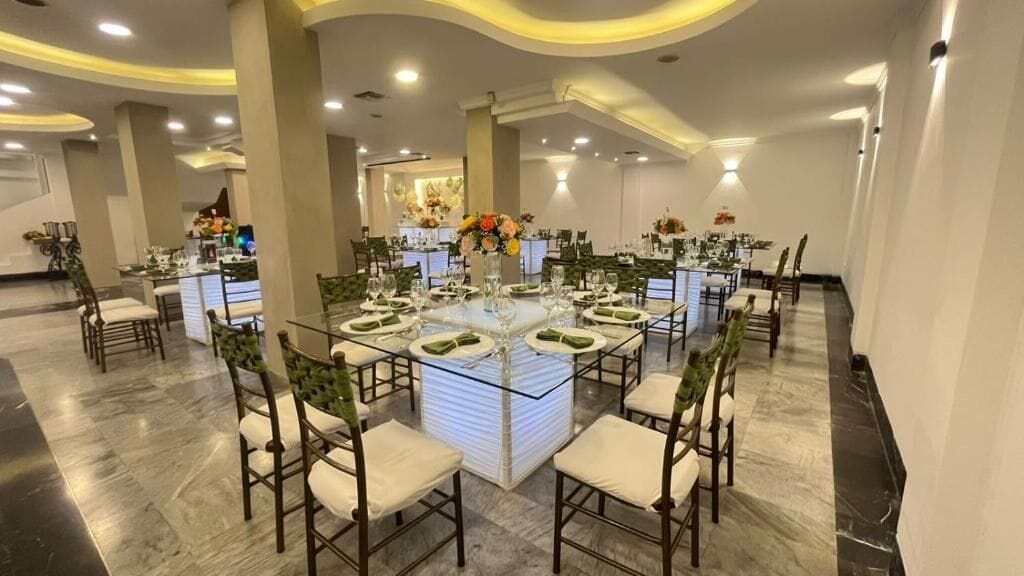 A banquet hall with round tables, chairs, and a central bar area.