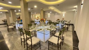 Un salón de banquetes con mesas redondas, sillas y una zona de bar central.