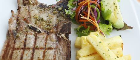 Un plato con carne a la parrilla, ensalada y papas fritas.