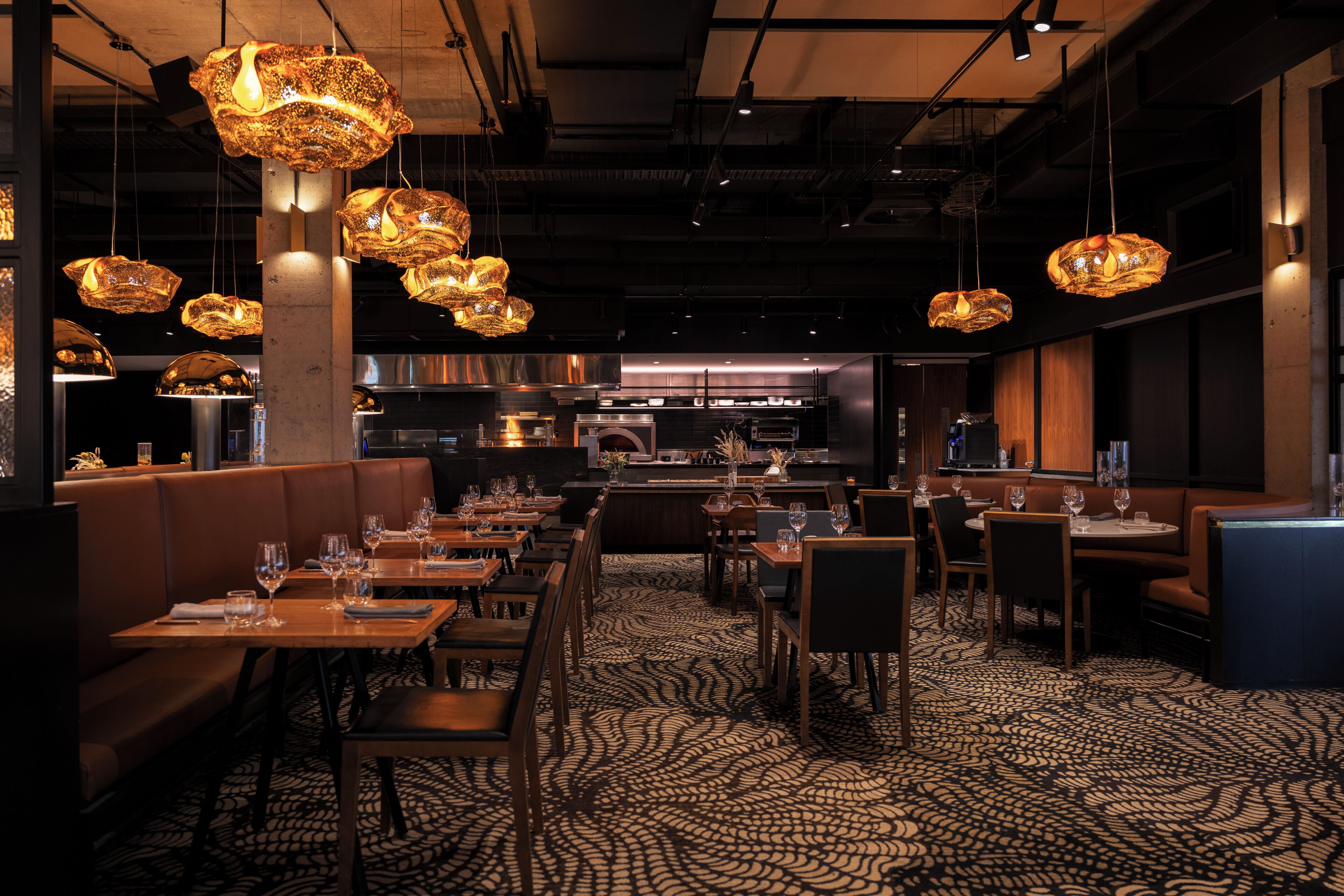 Ein Restaurantinneres mit Sitzecken, Tischen und hängenden Pendelleuchten.