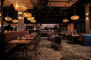 A restaurant interior with booths, tables, and hanging pendant lights.