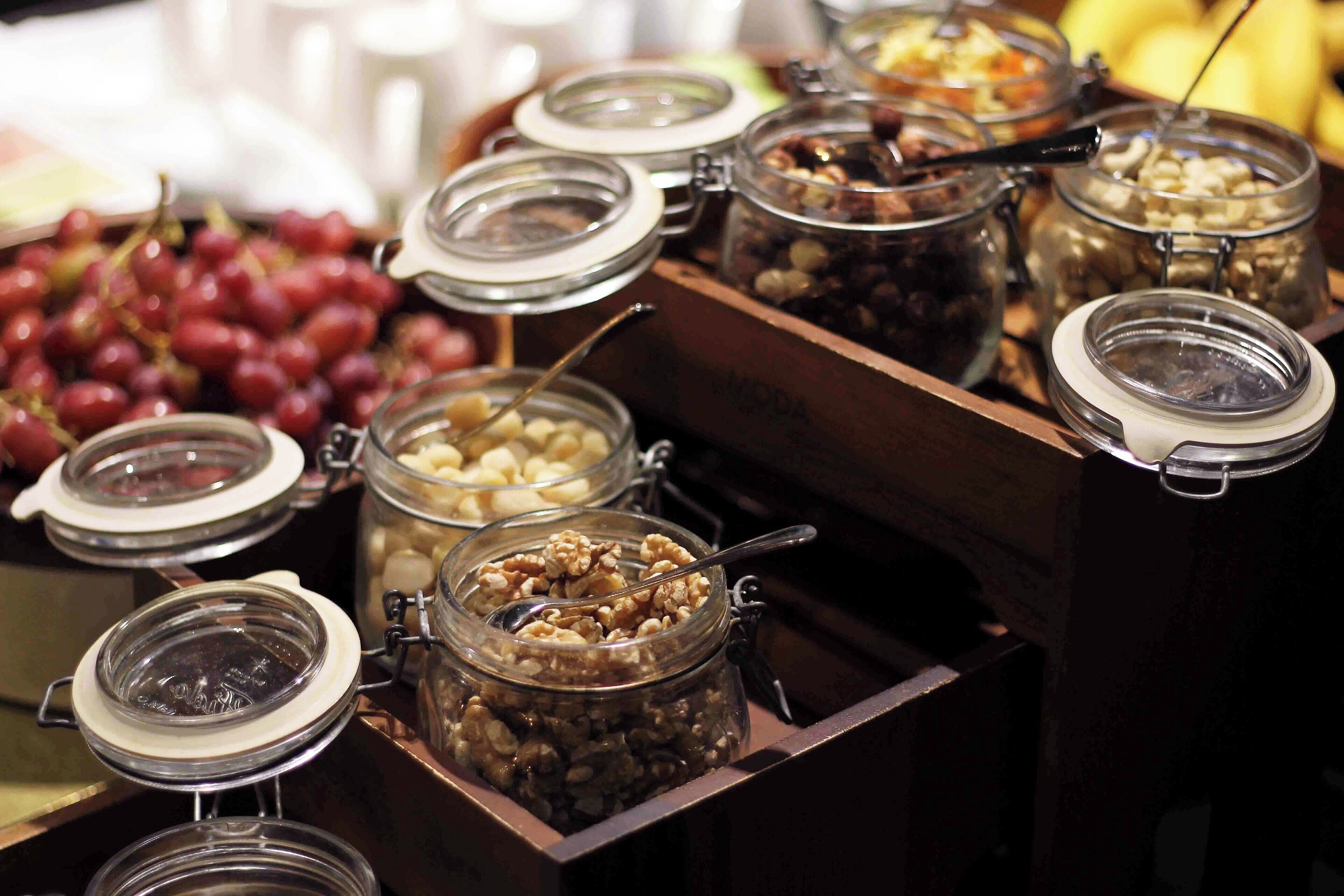A buffet with various food items in glass containers, including nuts and fruits.