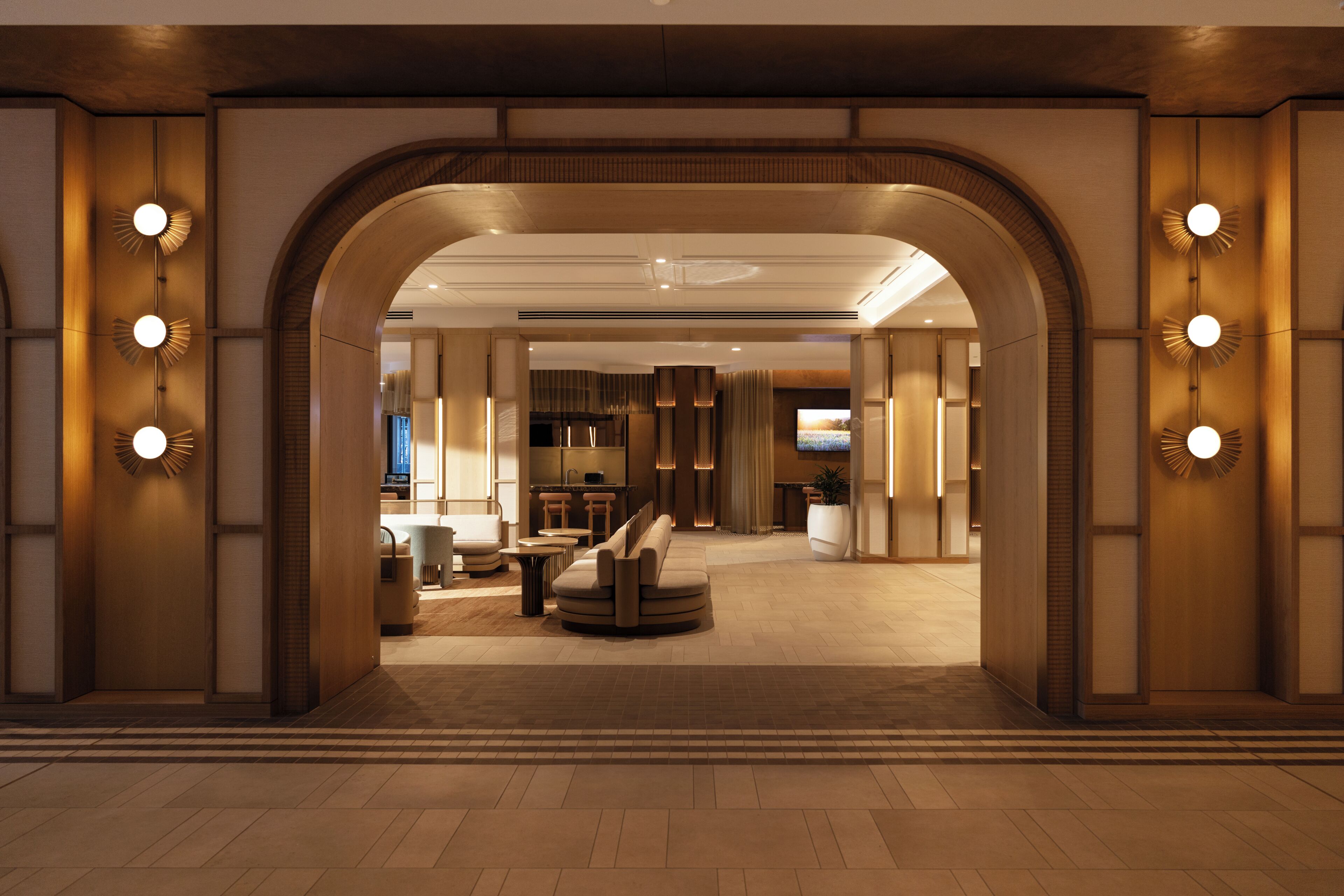 Eine Hotelhalle mit modernem Design, ausgestattet mit einer zentralen Sitzecke, einem Empfangsschalter und einem großen Bildschirm.