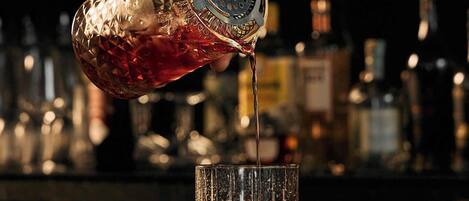 A hand pouring a drink from a crystal decanter into a glass.