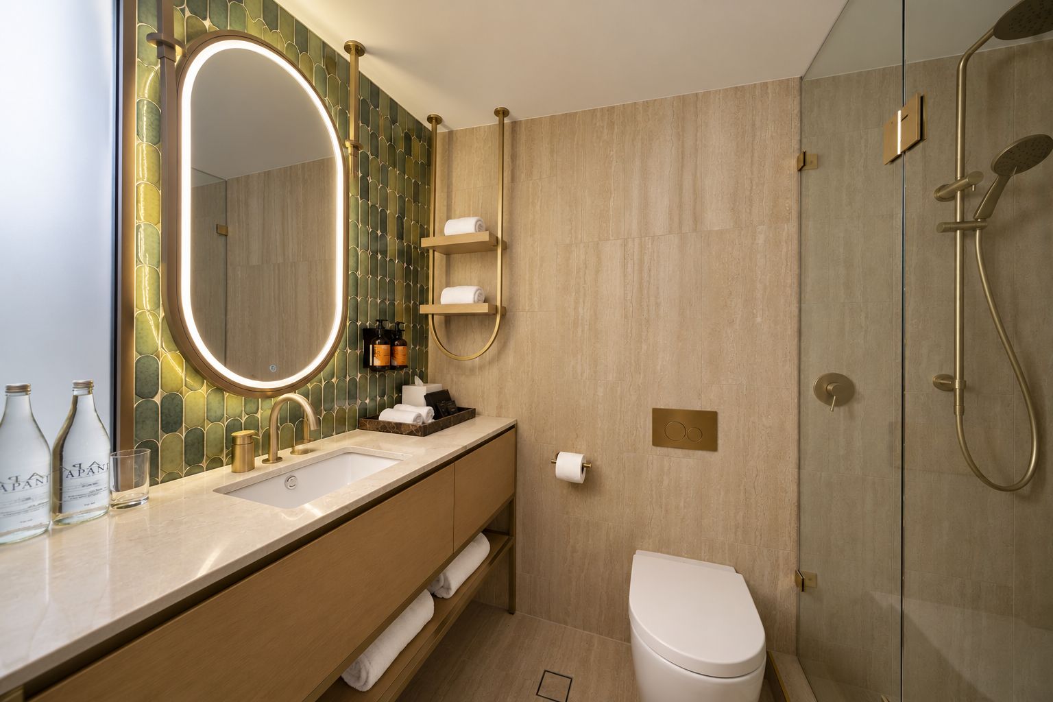 Et moderne badeværelse med et håndvaskarrangement, et stort spejl, en bruseniche og et toilet.