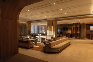Un hall d’hôtel moderne avec un espace salon, un bar et une cuisine visible au fond.