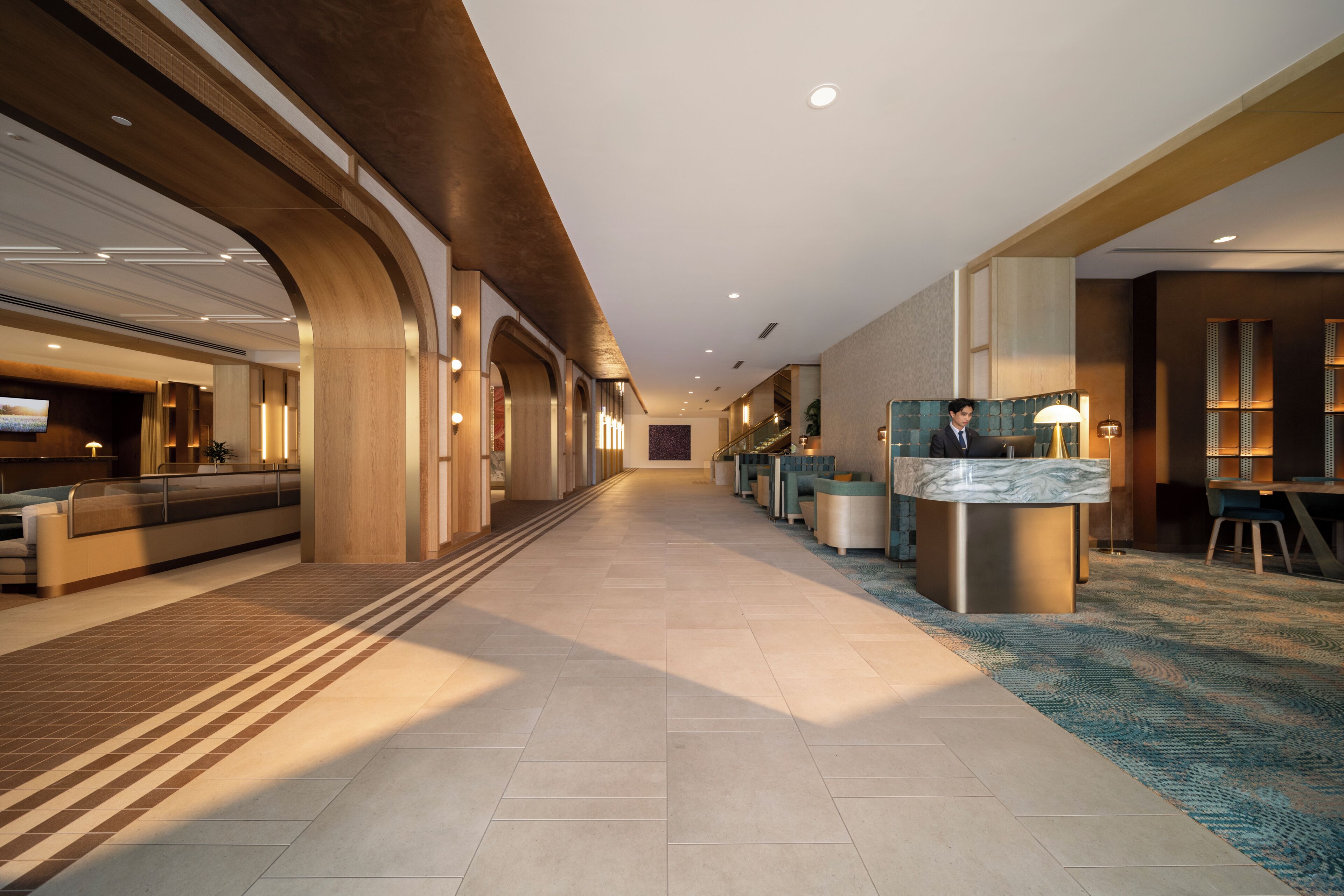 A hotel lobby with a reception desk, seating area, and a staircase.