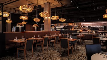 A restaurant interior with booths, tables, and hanging pendant lights.