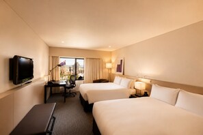 A hotel room with two beds, a desk with a computer, a TV, and a window with curtains. - Amora Hotel Adelaide (Adelaide)