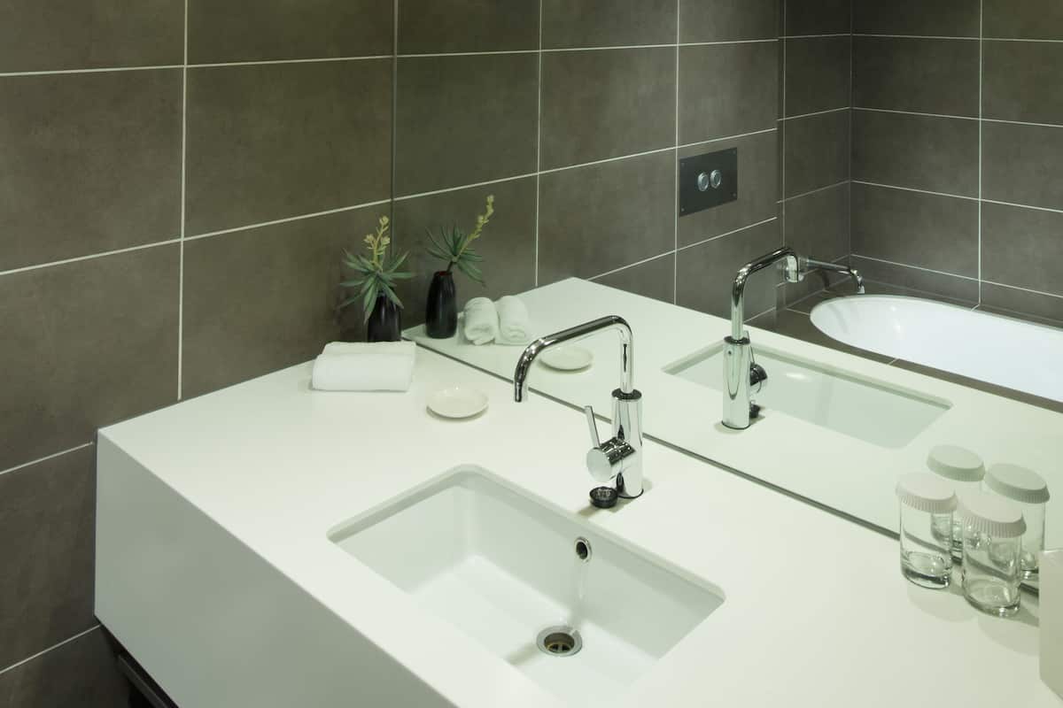 Une salle de bain moderne avec un grand miroir, deux lavabos et une baignoire.