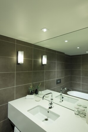 Une salle de bain moderne avec un grand miroir, deux lavabos et une baignoire.