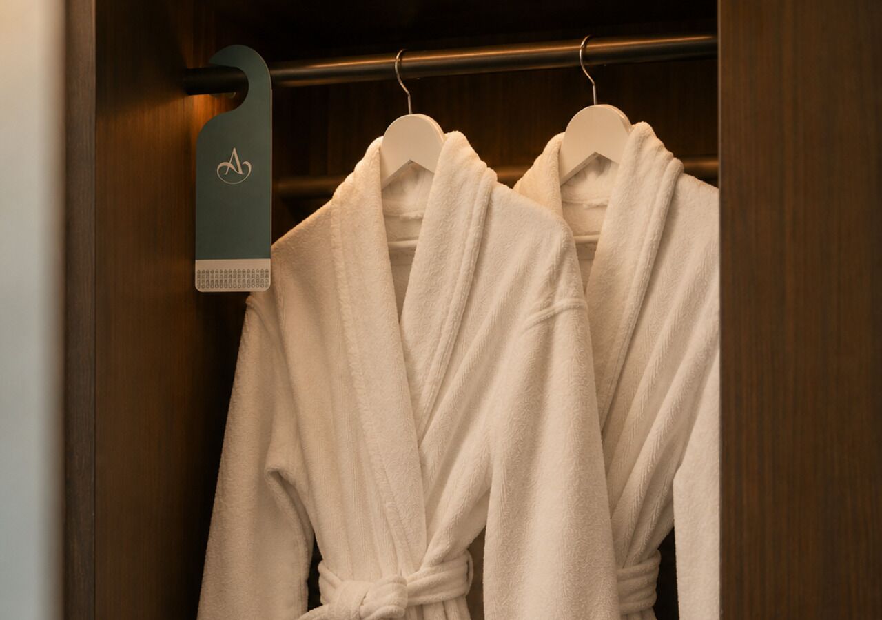 A wooden closet with two white robes hanging on white hangers.