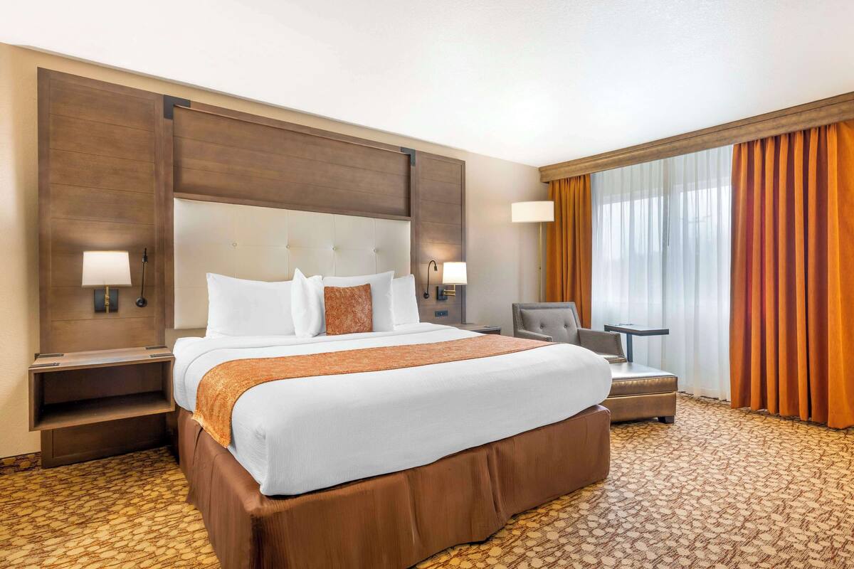 A hotel room with a large bed, two bedside tables, a desk, and a chair.