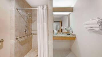 A bathroom with a shower, a sink, and a towel rack.