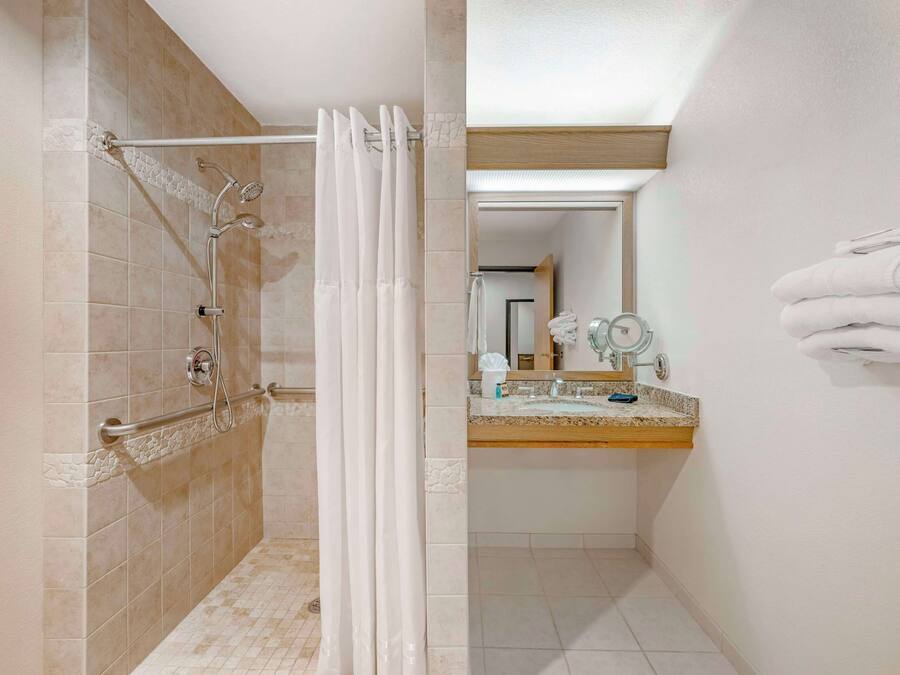 A bathroom with a shower, a sink, and a towel rack.