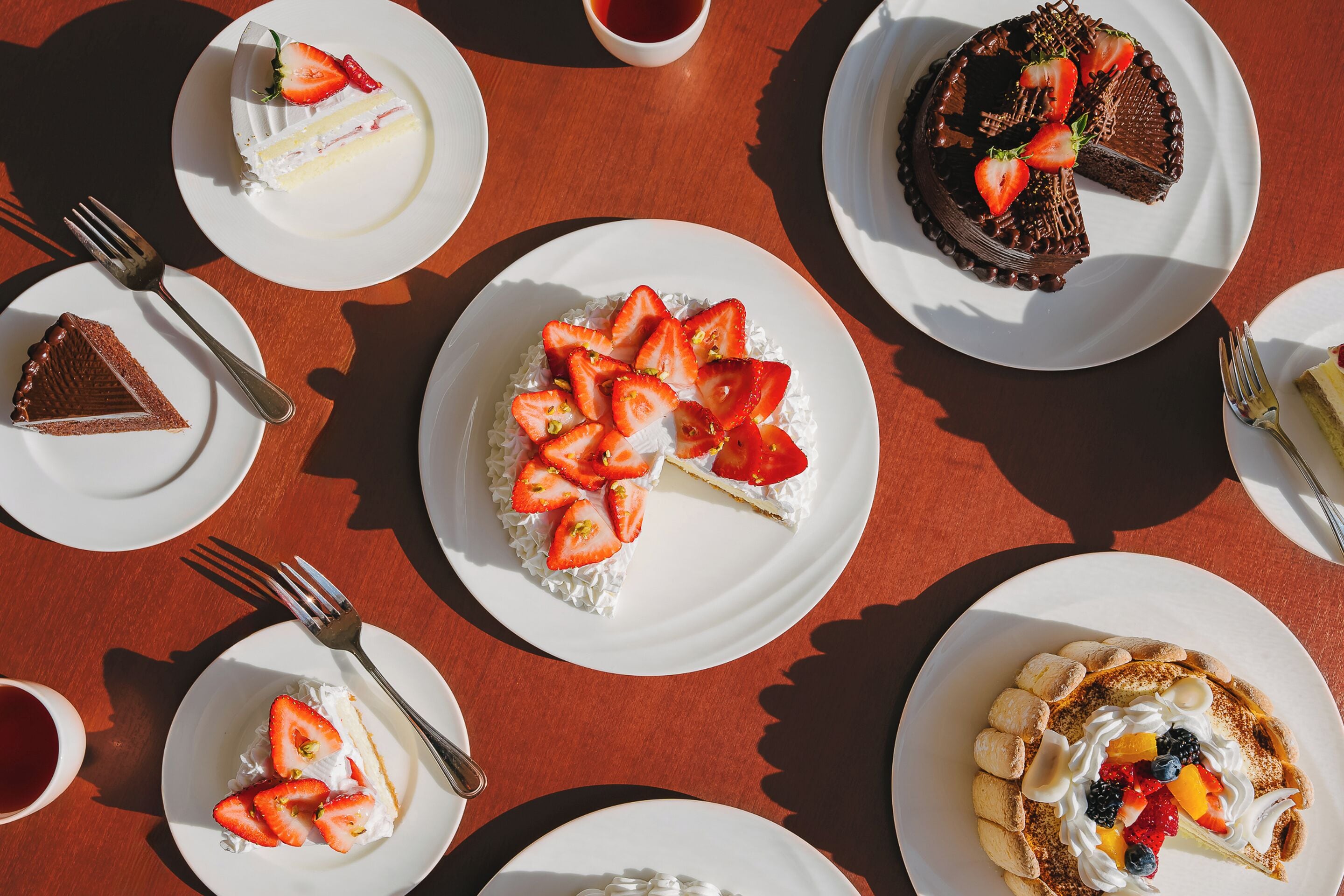 Une table où sont présentés divers desserts, notamment des gâteaux et des pâtisseries, disposés sur des assiettes blanches.