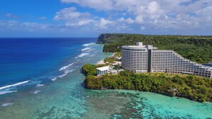 A large resort with multiple buildings, a beach, and a cliff overlooking the ocean. - Hotel Nikko Guam (Tamuning)