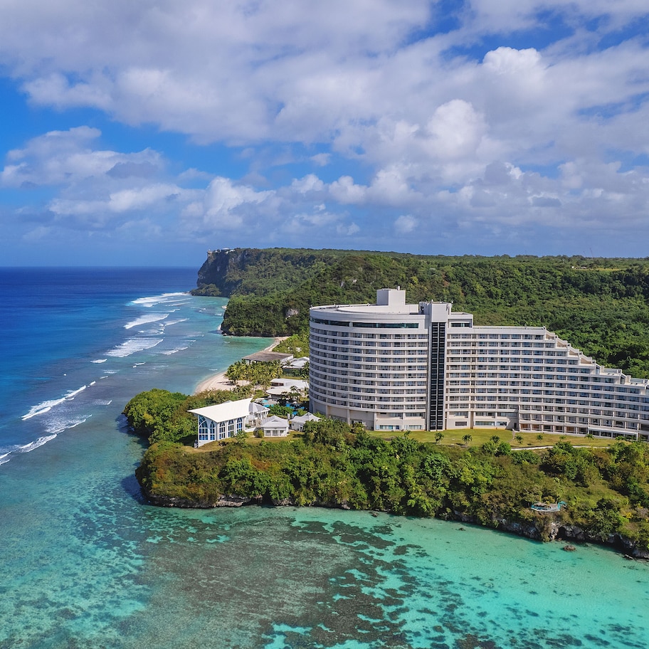 A large resort with multiple buildings, a beach, and a cliff overlooking the ocean.