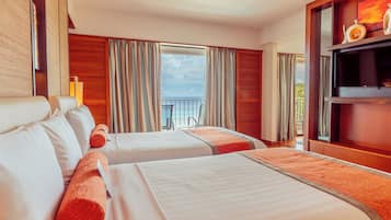 A hotel room with two beds, a balcony with a view, and a television on a wooden shelf.