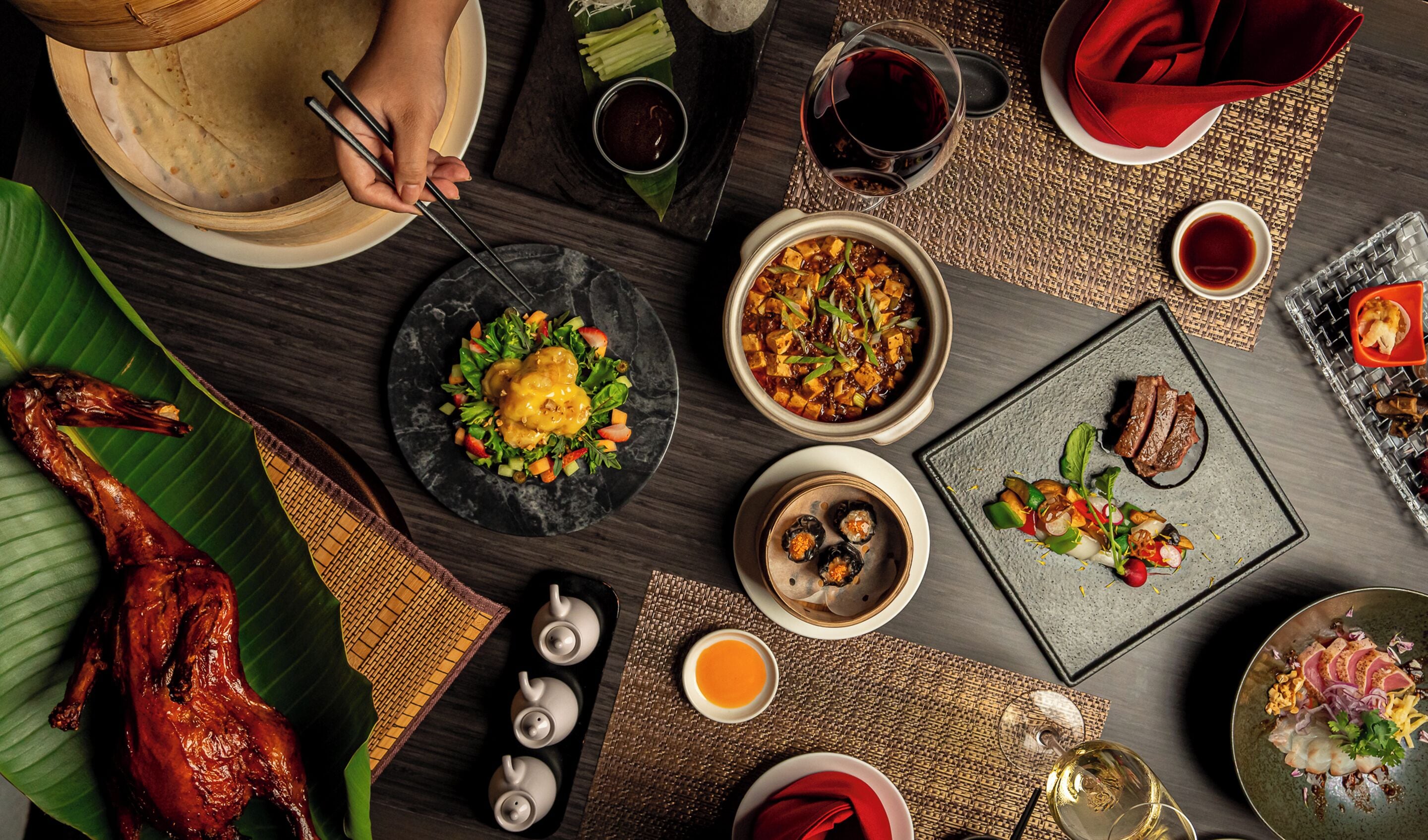 A table set with various dishes, including a roasted chicken, a bowl of soup, and several plates of food.