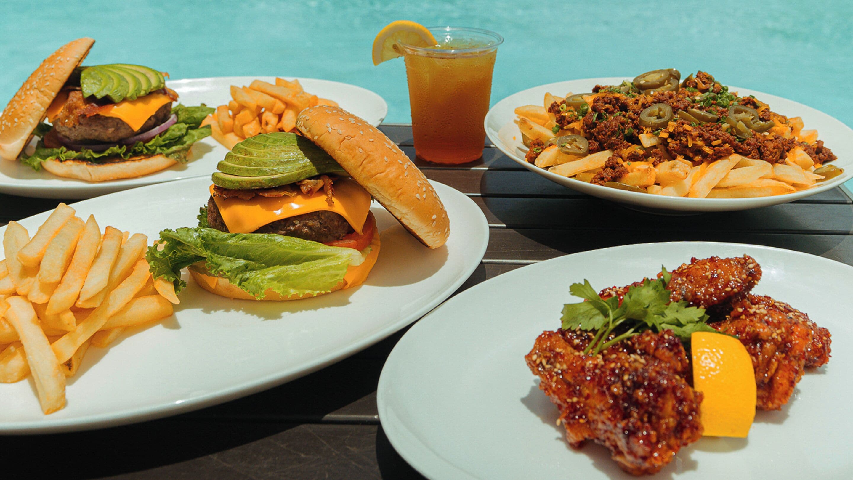 Una mesa con varios platos de comida, incluyendo hamburguesas, papas fritas y una ensalada.