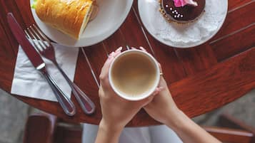 A table with a croissant, a chocolate cake, and a cup of coffee.