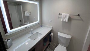 A modern bathroom with a large mirror, a sink, a toilet, and a towel rack.