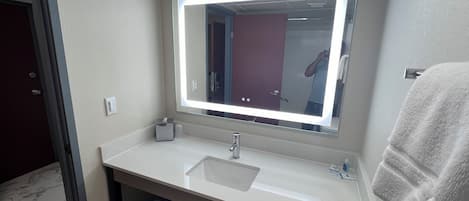 A bathroom with a large mirror, white sink, and a towel rack.