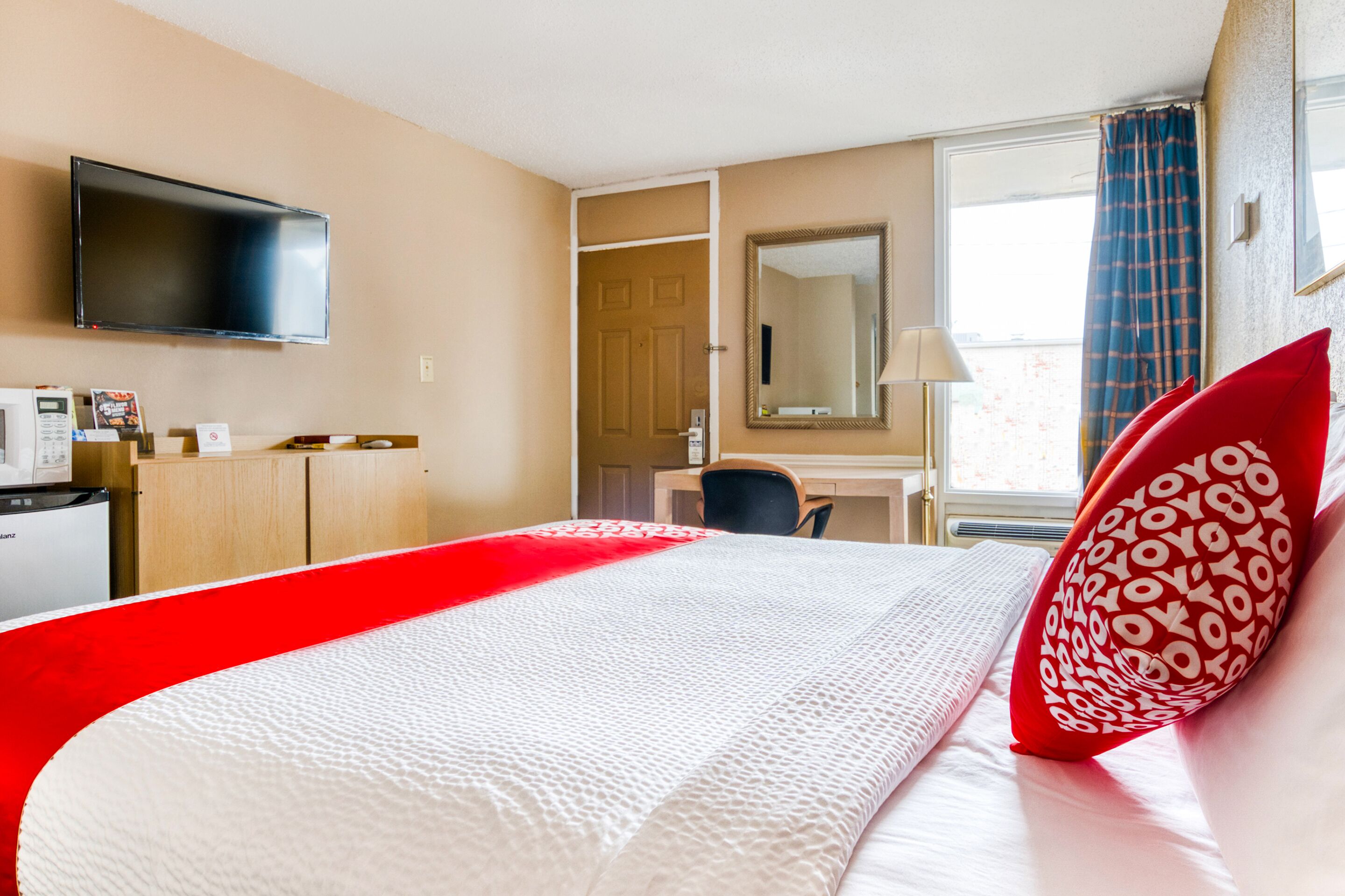 A hotel room with a bed, a desk, a television, a microwave, and a wardrobe.