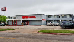 Un hôtel avec une enseigne « OYO HOTEL » bien visible, un parking avec plusieurs voitures et une pelouse bien entretenue.