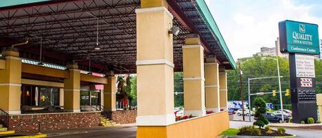 A hotel with a covered outdoor area, a signboard for Quality Inn & Suites Conference Center, and a parking lot.