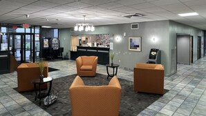 Eine Lobby mit orangefarbenen Sitzgelegenheiten, einem Empfangstresen und einem Verkaufsautomaten.