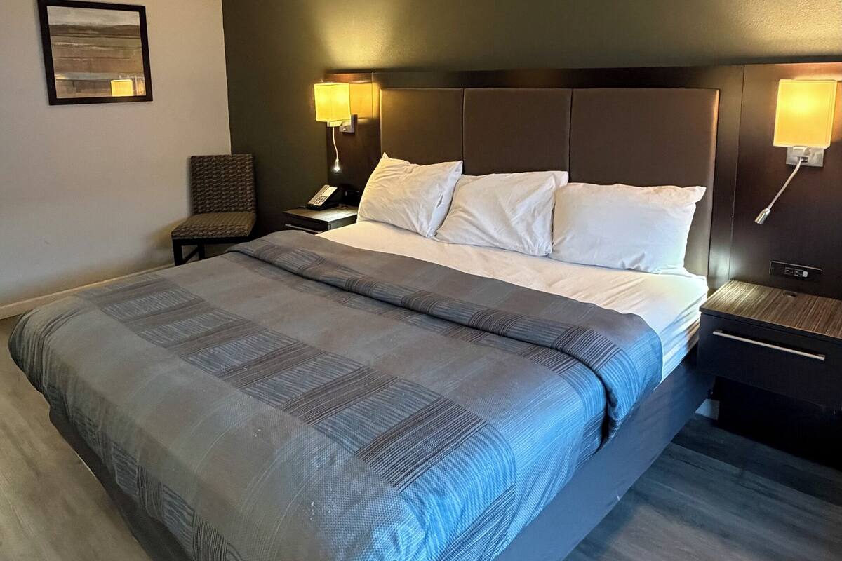 A large bed with a headboard, bedside tables, and wall-mounted lamps.