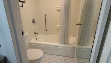 A bathroom with a toilet, bathtub, and shower area.