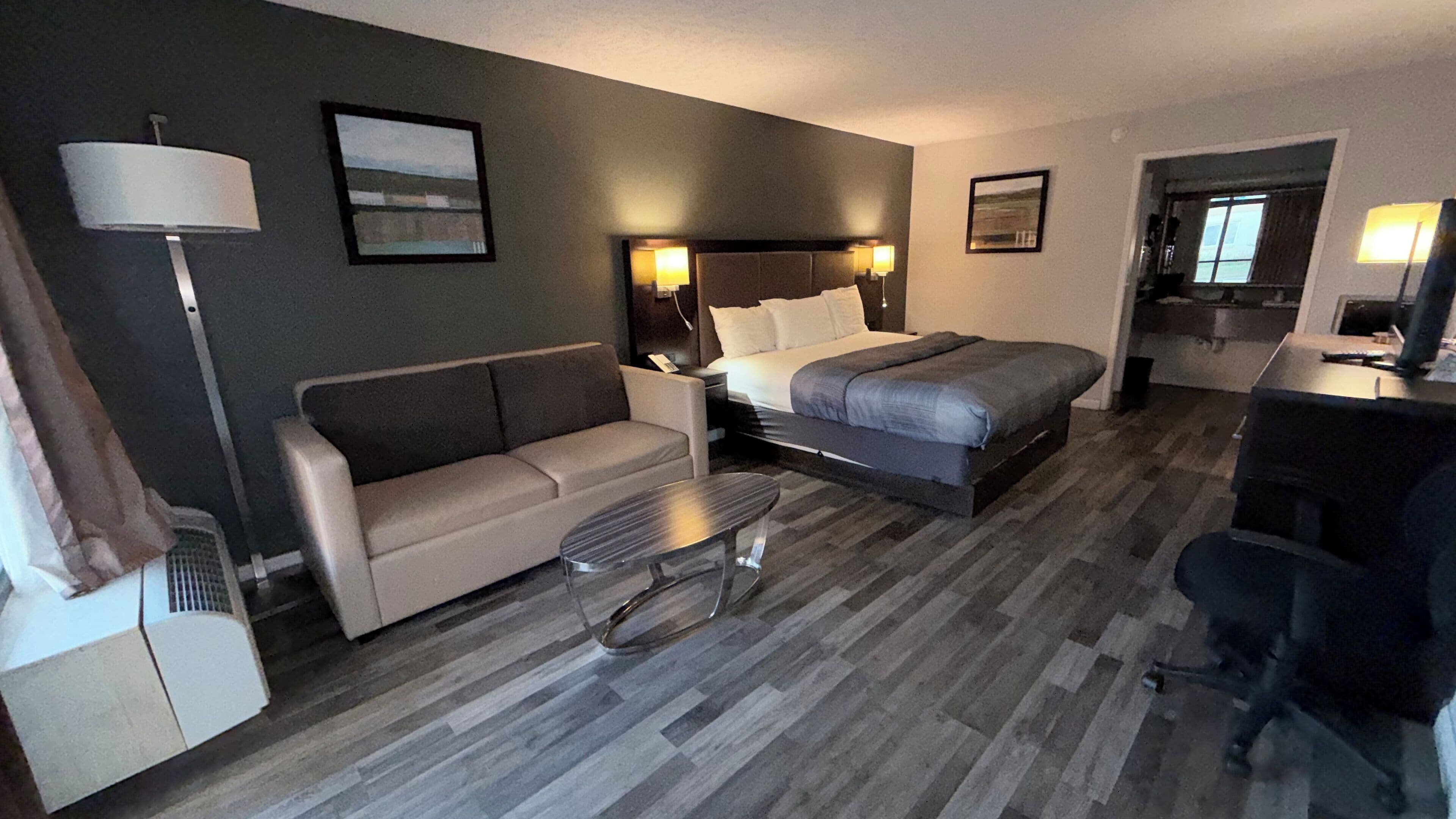 Una habitación de hotel con cama, sofá, escritorio y silla.